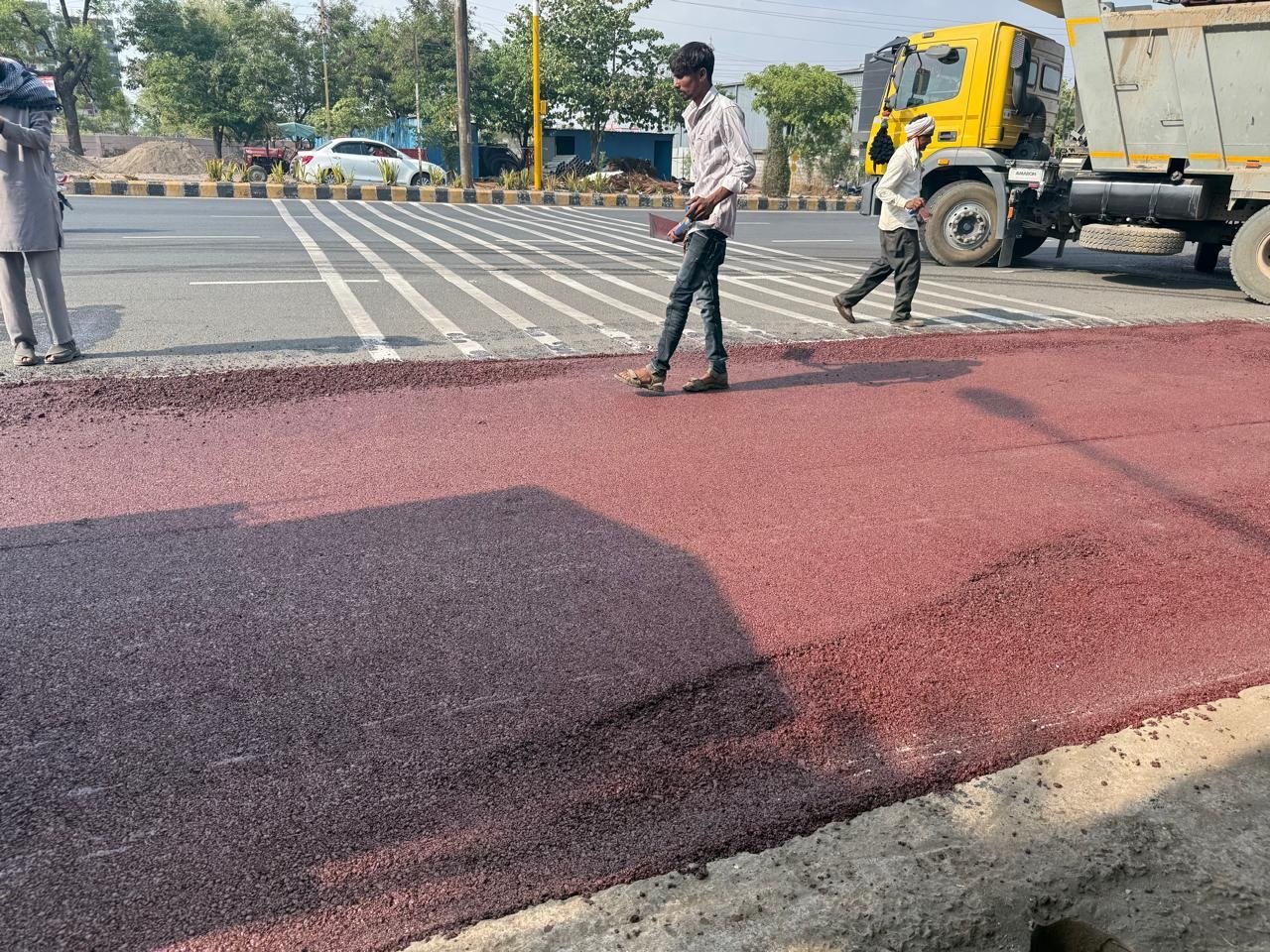 Finished red bitumen surface beside a zebra crossing